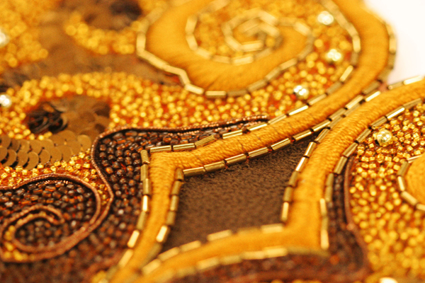 The teeny tiny pieces of hand embroidery & beadwork; detail of heart design in golds and browns. Photo courtesy The Alexanders