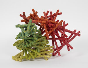 Christine K. Miller, <em>Inflammatory</em>, 2024. Wire, fiber, 13" x 10" x 11". Inflammatory displays how pain can feel sharp and hot in our bodies. When we have homeostasis, the cells and muscles feel smooth and aligned - energy flows easily and the green color represents harmony and growth in the body. The sharp contrast of the red, spiky and angular elements is creeping into the harmonious part of the sculpture.